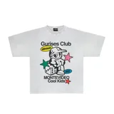 Remera blanca de algodón con corte boxy y estampado con el logo de Gurises Club, que incluye un personaje de caricatura, estrellas, un dado y la inscripción 'Montevideo Cool Kids'.