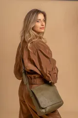 Bandolera de hombro color gris claro, con solapa frontal y correa ajustable. Presenta un diseño simple y práctico, ideal para uso diario.