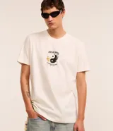Remera color crudo de algodón, corte comfort, con mangas cortas y cuello redondo. Estampa frontal y trasera con temática de japonismo, incluyendo un Yin Yang en llamas, un dragón y el texto "Duality - Chaos Order - Kyoto Japan".