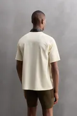 Camiseta deportiva marrón con estructura perforada, cuello redondo, manga corta y logo estampado.