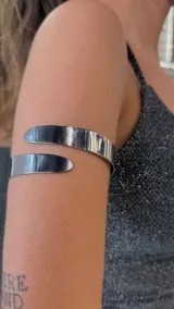 Brazalete plateado rígido para el brazo, abierto en la parte superior.