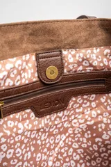 Bolso tipo tote de gamuza vegana color camel, con asas de mano y logo grabado en el frente.