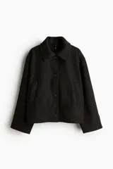 Campera corta negra de tejido de fieltro suave con cuello clásico y cierre frontal con botones. Modelo de corte holgado con hombros caídos y bolsillos insertados adelante.