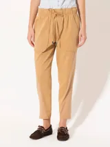 Pantalón babucha color beige, confeccionado en tejido de punto y plano, con cintura elastizada, cordón ajustable y largo al tobillo.