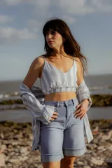 Conjunto de camisa y top corto a rayas verticales amarillas y blancas. El top es corto con tiras finas y elástico en la base. La camisa es de manga larga y corte relajado.