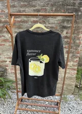 Remera negra de algodón con estampado digital de un vaso con rodajas de limón y la frase "summer flavor".
