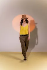 Pantalón de lino color marrón, con corte tipo barrel, tiro medio, pretina ancha con doble abotonadura, bolsillos laterales y pinzas en el frente. Ruedo con presilla permitiendo usarlo recto o fruncido al tobillo.
