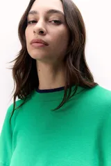 Sweater de punto verde con calce corto y amplio, con mangas acampanadas y línea en contraste en el cuello.
