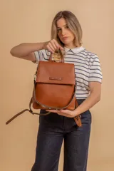 Mochila color verde oliva, tipo cartera, con tapa y doble cierre. Tiene dos compartimentos y división interna, además de un bolsillo trasero con cierre.