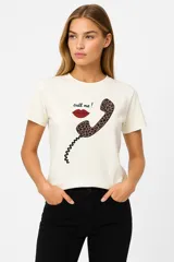 Remera de algodón color crudo con estampado de un labial rojo y texto en color bordó que dice "It's OK to wear lipstick". Corte clásico, cuello redondo y mangas cortas.