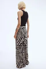 Pantalón amplio de sarga con estampado de cebra en tonos beige y negro, tiro alto, bolsillos al bies y cierre con botón y corchete ocultos.