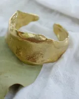 Brazalete rígido plateado con textura irregular.