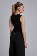 Musculosa marrón de tejido liso, con cuello redondo y tachas metálicas decorativas en los hombros.