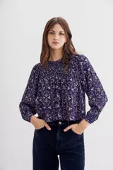 Blusa amplia de mangas largas y cuello redondo, estampada con detalles de lurex, punto smock en el frente y frunces en la espalda.