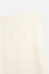 Pantalón color crema de corte amplio, con cintura elástica ajustable con cordón, bolsillos laterales y trasero, cierre frontal con cremallera y botón.