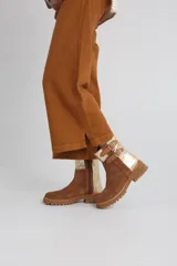 Botas cortas de gamuza color marrón con detalles dorados y hebillas decorativas.