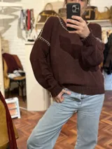 Sweater marrón de punto con cuello redondo y bordados blancos en escote y hombros.