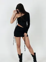 Conjunto de top asimétrico de un solo hombro y falda corta con cordones laterales ajustables.