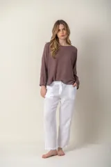 Pantalón de lino blanco, de corte recto y tiro medio, con bolsillos laterales y cierre frontal con botón y cremallera.