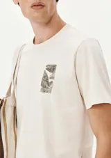 Camiseta beige de manga corta con estampa de hojas en el bolsillo.