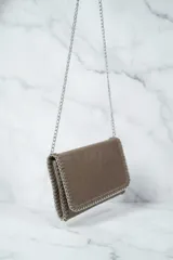 Cartera tipo sobre o clutch negra con textura de cuero envejecido. Presenta bordes decorados con costuras gruesas en contraste y una cadena metálica plateada que sirve como borde y correa de hombro.