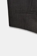 Chaleco gris oscuro con textura, escote en V, sin mangas, bolsillos frontales y cierre con botones.