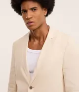 Saco de traje social color beige, confeccionado en viscolino, con cuello en V, cierre abotonado, bolsillos y medio forro.