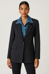 Blazer negro de corte clásico con solapas smoking, cierre con un botón y bolsillos laterales con solapa.