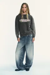 Sudadera gris con efecto lavado, cuello redondo, manga larga y rib en puños y bajo. Estampado frontal con el logo de Las Super Nenas.