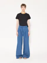 Pantalón de cintura alta confeccionado en denim camisero liviano, color celeste. Presenta piernas amplias con tablas frontales, bolsillos laterales y ojales sastres en la espalda.