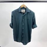 Camisa de manga larga verde petróleo con cuello italiano y logo bordado en el pecho.