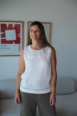 Musculosa blanca de lino, con cuello redondo y un canesú horizontal sobre el pecho. Presenta un detalle de pespunte negro en el ruedo inferior.