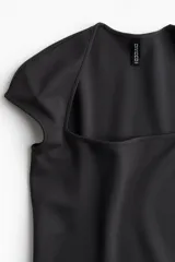 Vestido corto negro de punto, ajustado al cuerpo, con escote cuadrado, mangas japonesas y abertura lateral.
