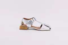 Sandalias plateadas de cuero con punta abierta, tira central y hebilla lateral. Taco cuadrado de madera.