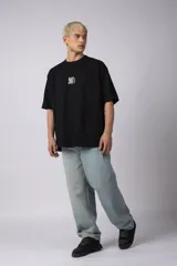 Remera color crema de corte oversize con la inscripción '90's' bordada en el frente y parche con imagen en la espalda.