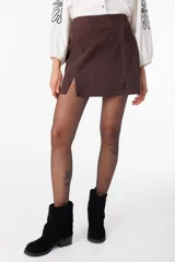 Minifalda marrón de cuero descarne, corte recto con abertura frontal.