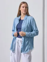 Camisa de jean celeste con flecos en el ruedo, de mangas largas y corte recto.