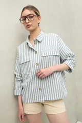 Chaqueta a rayas verticales celestes y blancas, con cuello camisero, cierre frontal con botones, dos bolsillos de parche en el pecho y mangas largas con puños abotonados.