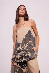 Top strapless color beige con estampado de hojas negras.