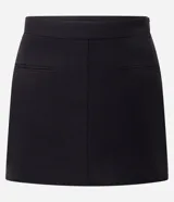 Short pollera negro ajustado, confeccionado en tejido plano de estructura sastre, con pences, cierre lateral por cremallera invisible y mini bolsillos delanteros.