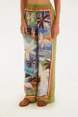 Pantalón largo de corte fluido con estampado de palmeras y motivos playeros, cintura alta con cordón ajustable y ribete naranja en ruedo y laterales.