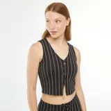 Top corto estilo chaleco de traje negro con rayas verticales blancas, escote en V y cierre frontal con botones.