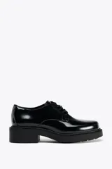 Zapato tipo mocasín acordonado de charol negro con punta redonda y suela track de 4 cm de altura.