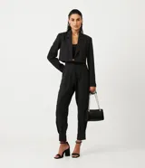 Pantalón zanahoria de crepé negro con pliegues, corte de sastrería, trabillas en la cintura y abertura con botón y cremallera.