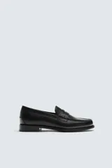 Mocasín de vestir negro de piel, con antifaz en el empeine y suela a tono con ligero tacón.