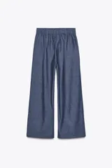 Pantalón azul de tiro alto con pinzas y nervio marcado delantero, cintura elástica en la espalda, pernera ancha y cierre frontal con cremallera, botón interior y ganchos.