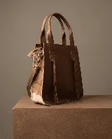 Cartera tote de cuero vacuno color marrón con laterales de cuero con pelo de vaca blanco y marrón. Tiene doble asa corta y correa larga desmontable.