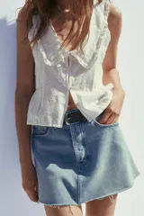 Minifalda de jean celeste de tiro medio, con trabillas, cinco bolsillos y ruedo desflecado.