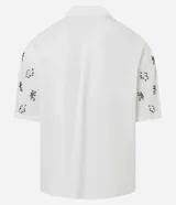 Camisa de manga corta para hombre, corte boxy, color blanco con cuello bowling y un estampado repetitivo de figuras geométricas negras.