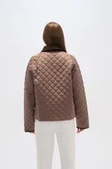 Campera marrón con diseño acolchado, cuello de pana marrón, cierre con botones a presión y bolsillos laterales.